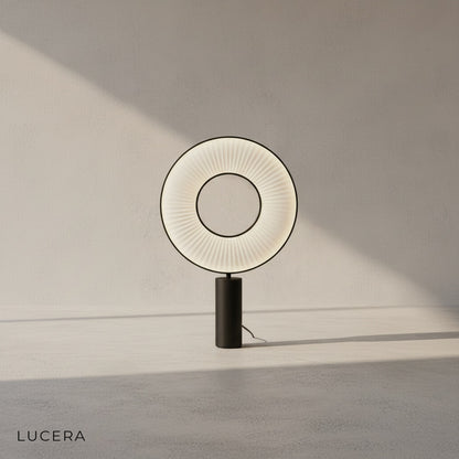 Close-up of Brio lamp's pleated fabric texture and brushed metal stem in warm ambient light