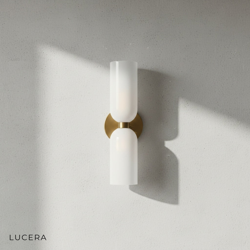 Close-up detail of brushed brass backplate and glossy white glass shade on Dolce double sconce