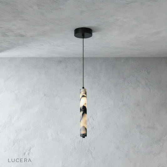 studio shot of a slender cylindrical marble pendant light on a clean white background