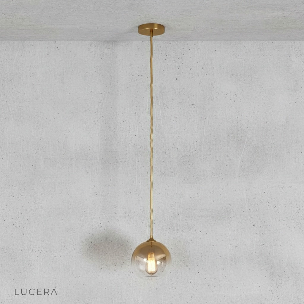 Studio shot of green gold spherical glass pendant light against clean white background