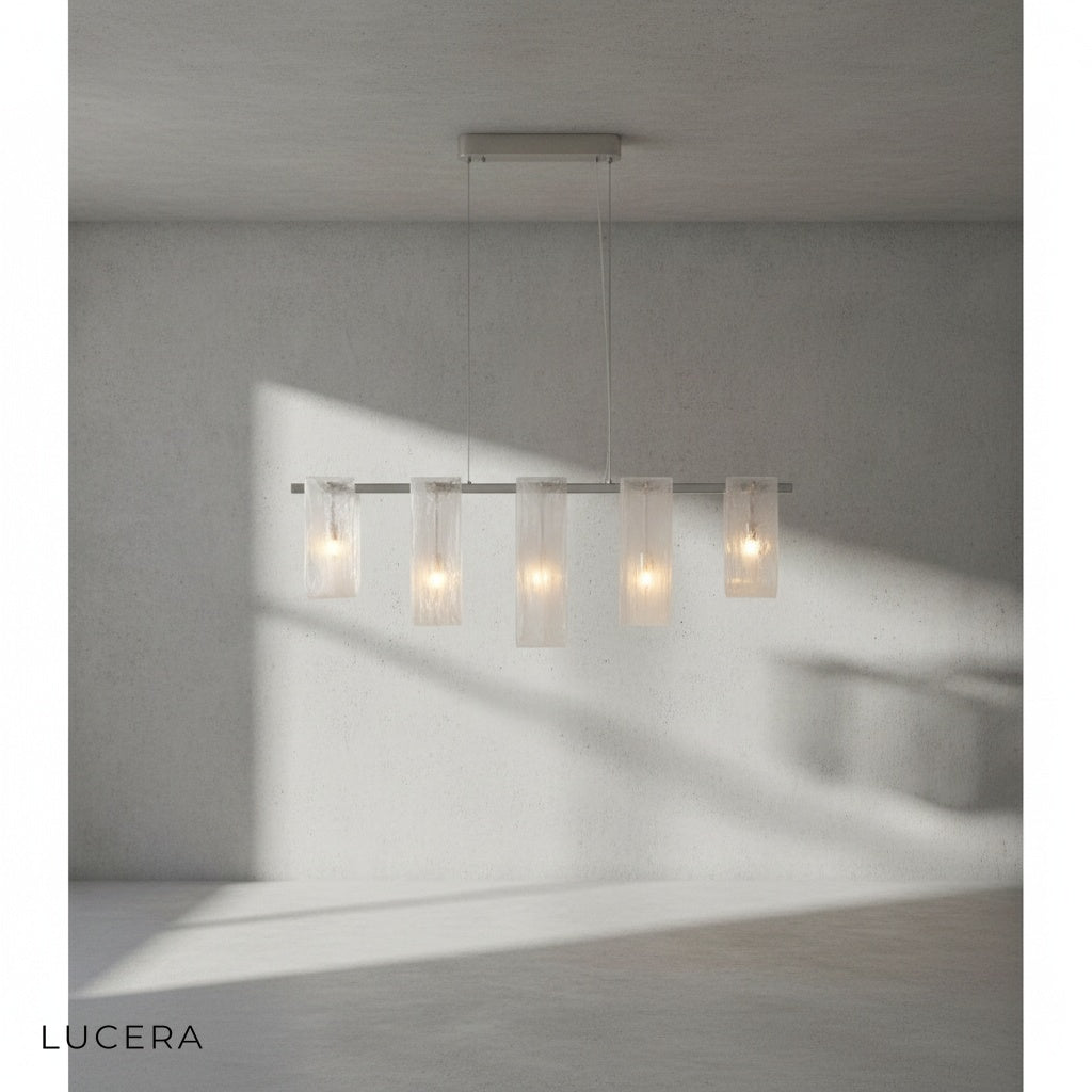 Fuchsia Liora linear pendant light hanging above a kitchen island with bar stools in bright daylight