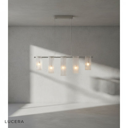 Fuchsia Liora linear pendant light hanging above a kitchen island with bar stools in bright daylight