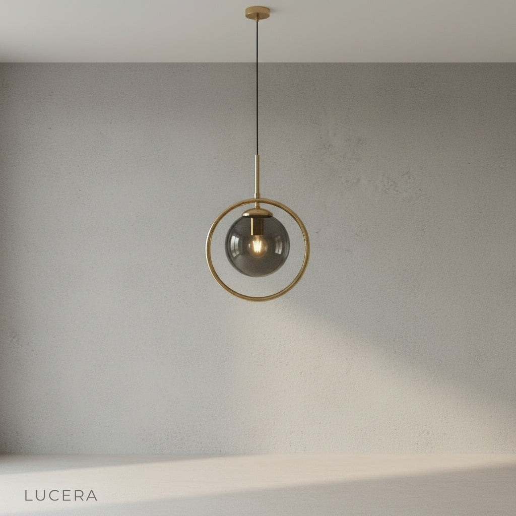 Caelus pendant light front view against neutral gray backdrop highlighting clear glass and gold finish