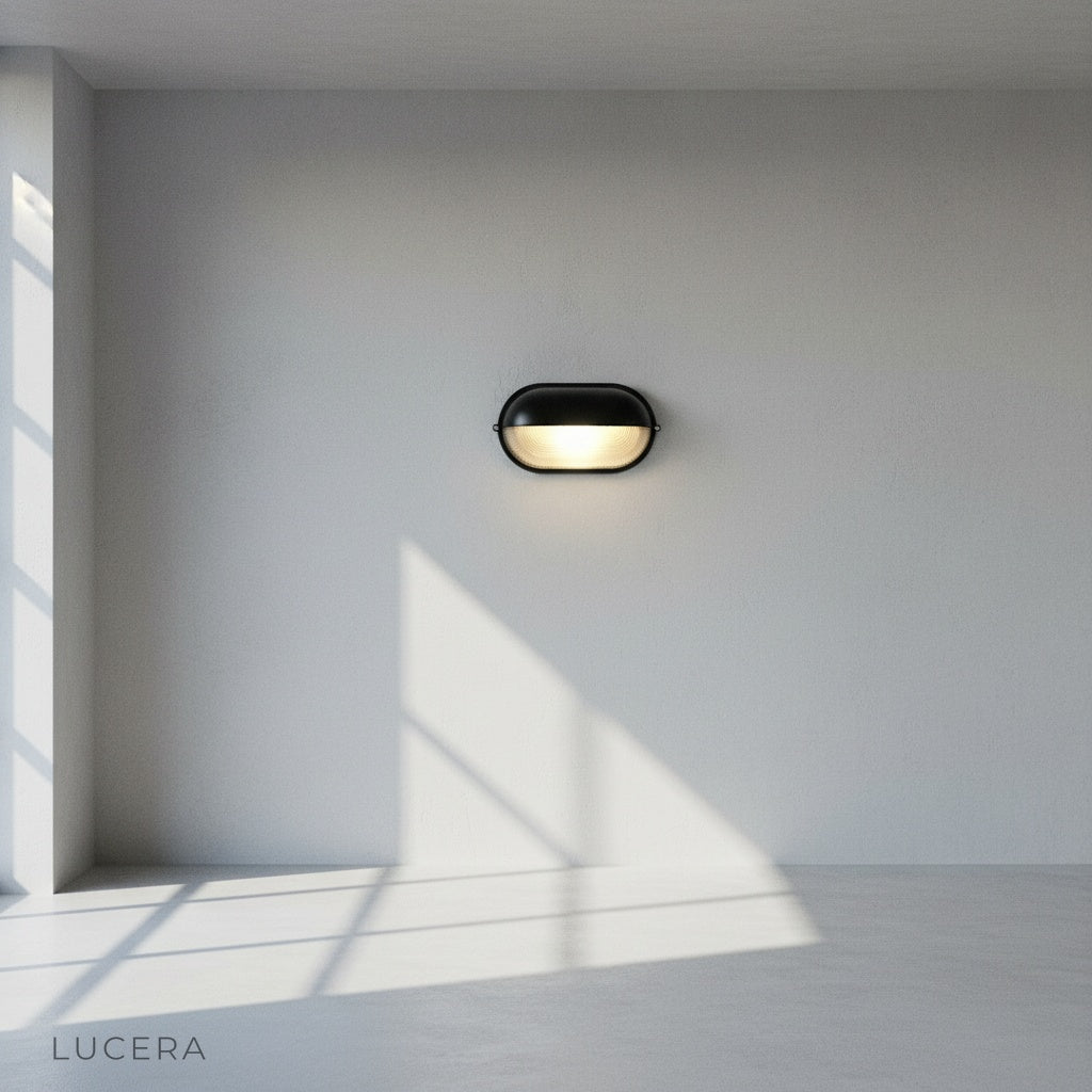 side angle studio shot of industrial-style Acolyte wall sconce with glass shade