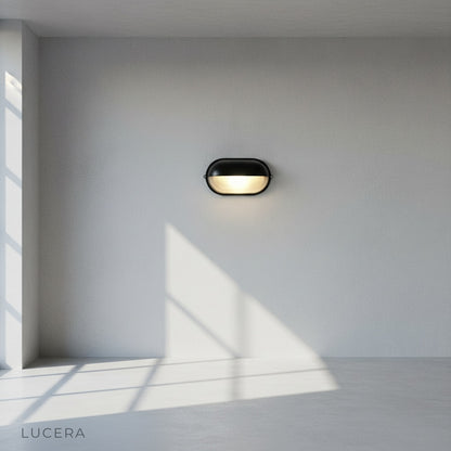 side angle studio shot of industrial-style Acolyte wall sconce with glass shade