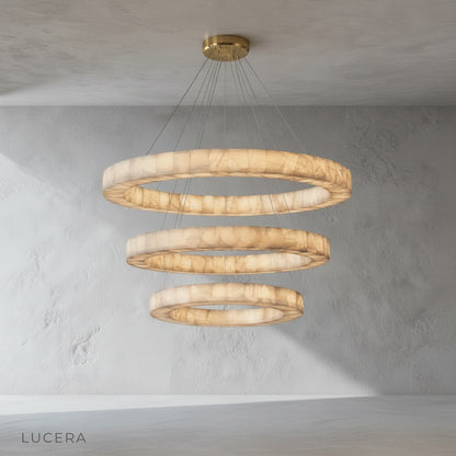 The chandelier hanging above a bathtub in a spa-like bathroom, with soft diffused light and stone tiles