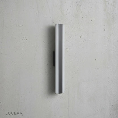sleek Drambuie fixture mounted on white stucco wall with soft shadow play at sunset