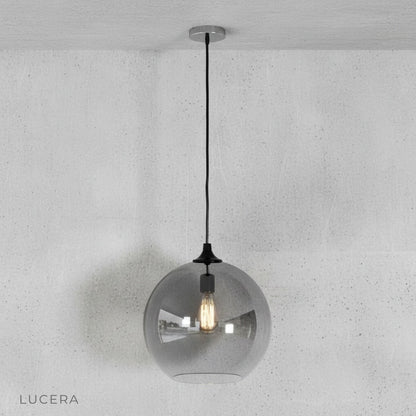 Green gold ombre pendant light hanging low over a rustic wooden table in a loft