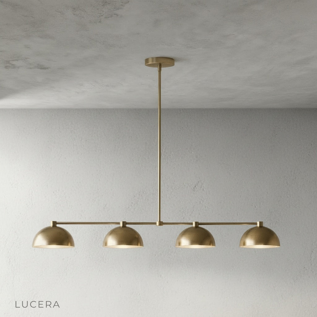 Close-up detail of smooth brass finish and curved dome shade on Ursule linear pendant light