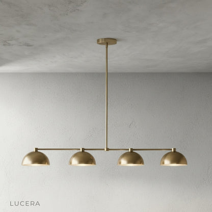 Close-up detail of smooth brass finish and curved dome shade on Ursule linear pendant light