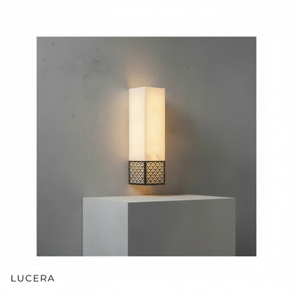 Vertical Astragal marble wall lamp illuminating dark textured wall with soft 3000K glow