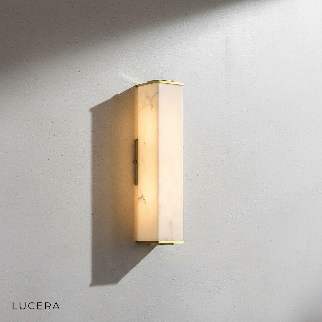 Brass and marble wall lamp detail highlighting natural stone texture and metal seams