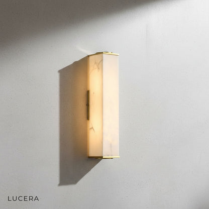 Brass and marble wall lamp detail highlighting natural stone texture and metal seams