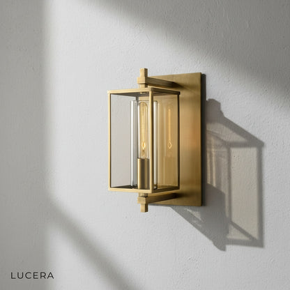 Brass glass wall lamp mounted on a brick wall in an outdoor patio setting