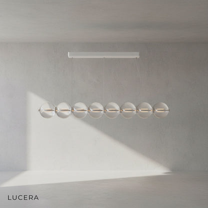 Linear chandelier with glass balls hanging above a stylish bar counter
