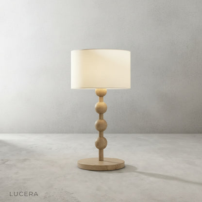close-up detail of Boreal Table Lamp stacked sphere wood base with warm ambient light through fabric shade