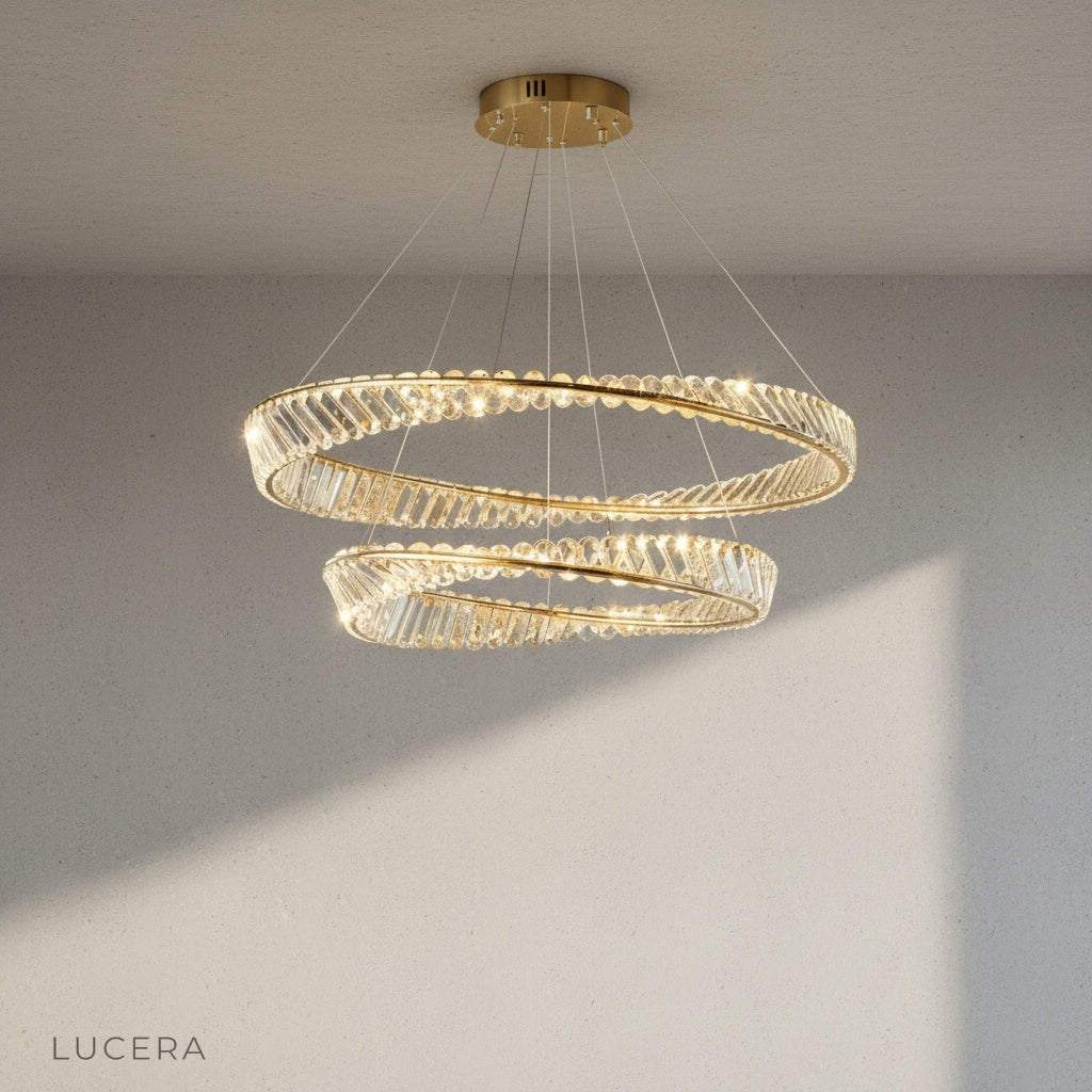 Umbilicus chandelier in polished metal finish with clear crystal accents against neutral wall