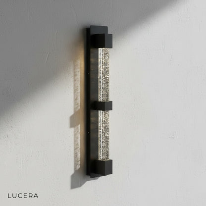 Hemera Outdoor Sconce casting soft light on a stucco wall in twilight