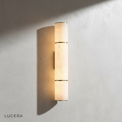 small Vague marble wall lamp casting warm glow in cozy reading nook with linen armchair