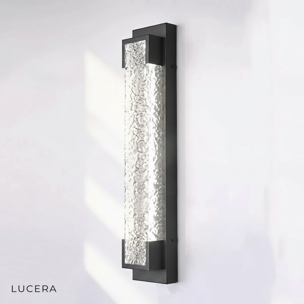 contemporary black stainless steel sconce lighting up a modern entryway at night