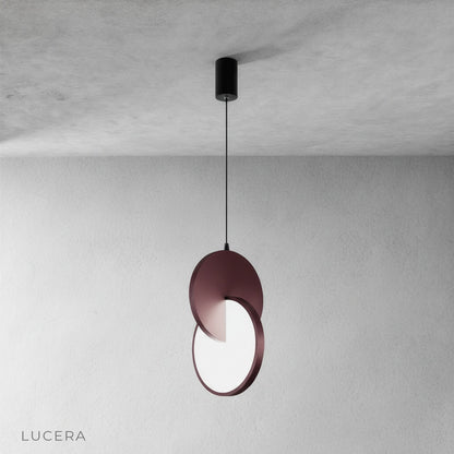 contemporary kitchen island lit by layered disc pendant light with shadow play on countertop