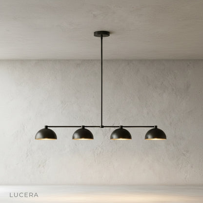 Ursule brass linear pendant light illuminating dining table with soft sculptural shadows