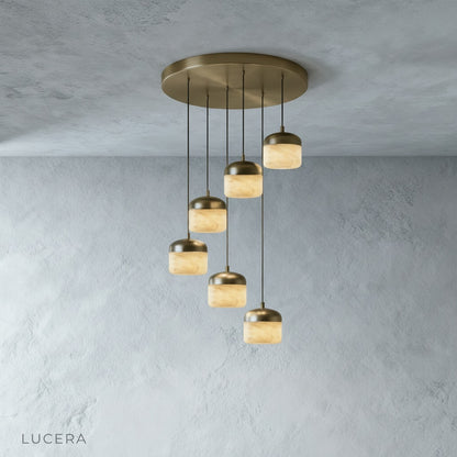 Energico alabaster pendant light hanging above a kitchen island with stools