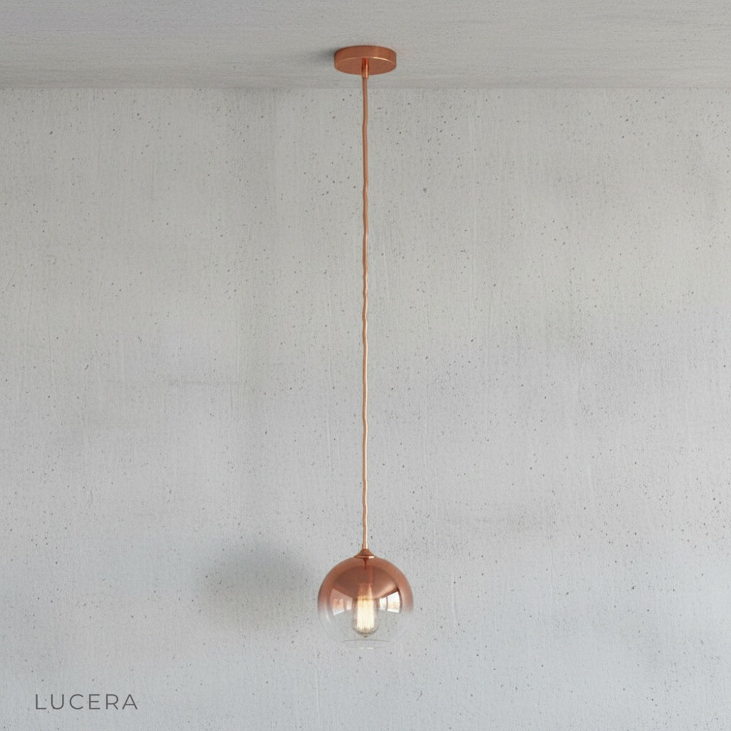 Close-up of smooth glass shade showing metallic green gold ombre finish and warm bulb