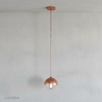 Close-up of smooth glass shade showing metallic green gold ombre finish and warm bulb
