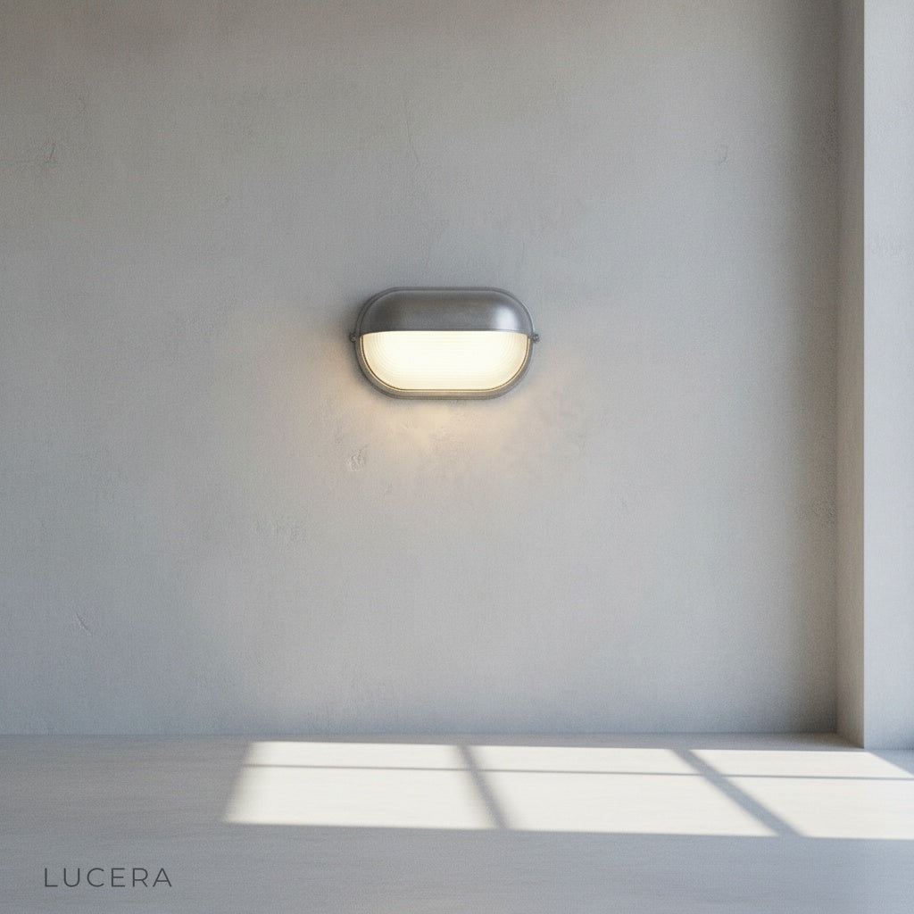 Acolyte wall lamp with warm LED glow against dark wood exterior wall