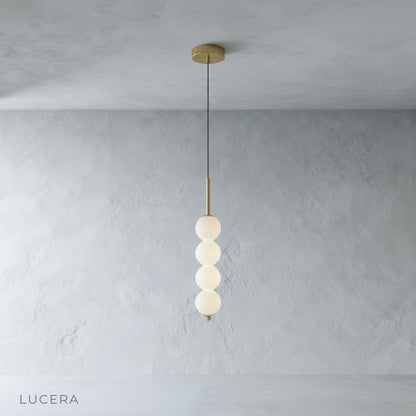 Meridian Pendant Light with five glass shades hanging above wooden dining table in bright room