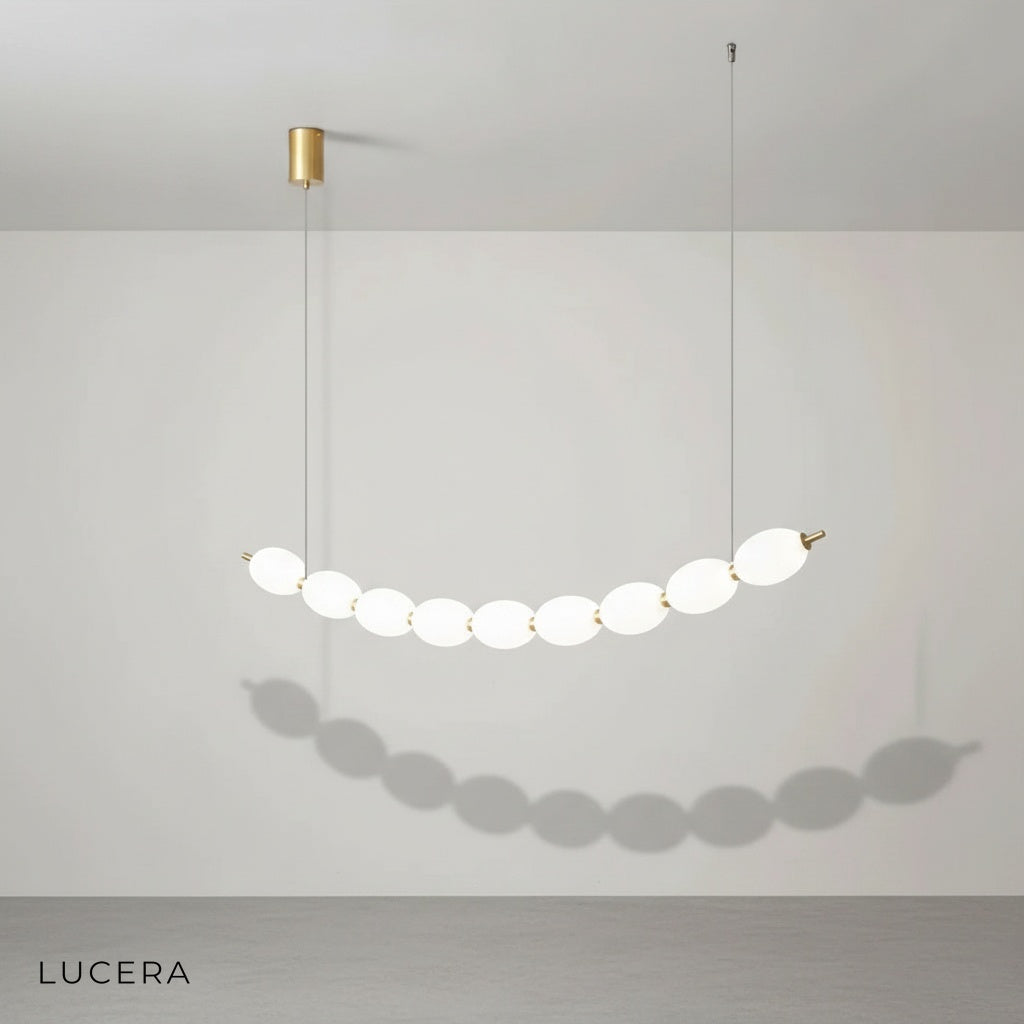 Warm LED glow illuminating chrome string of pearls chandelier in minimalist hallway with neutral walls
