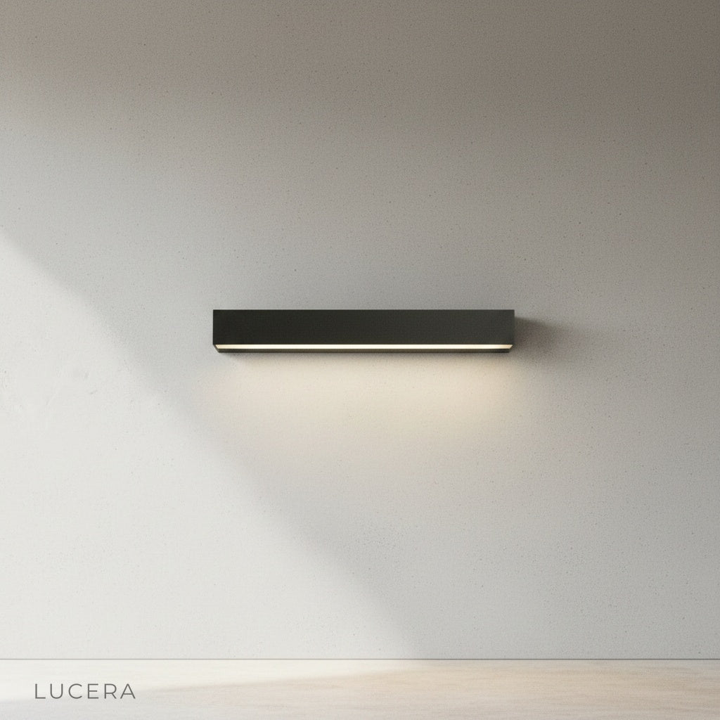 Goccia wall lamp in matte black finish mounted on brick wall, daytime natural light