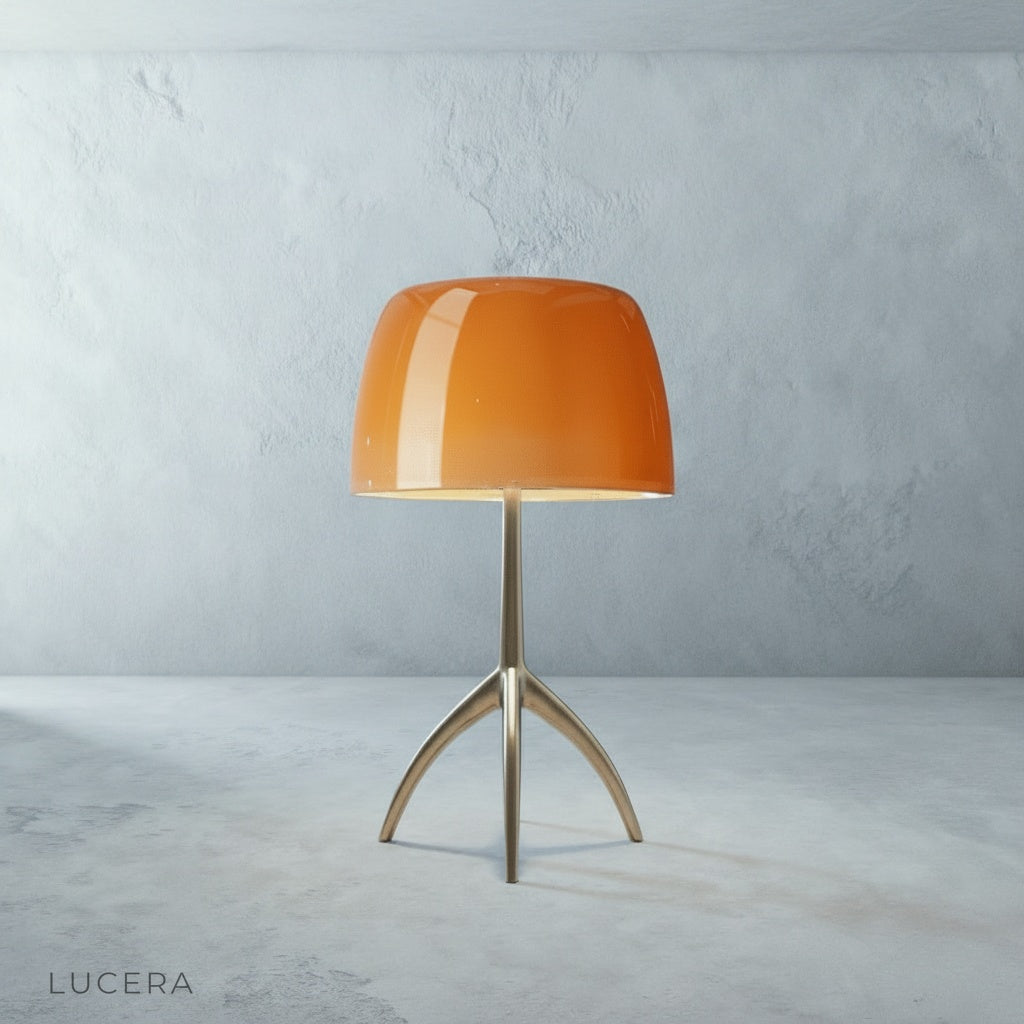 Albescent Table Lamp with brass tripod base on a wooden desk next to stacked books and a notebook