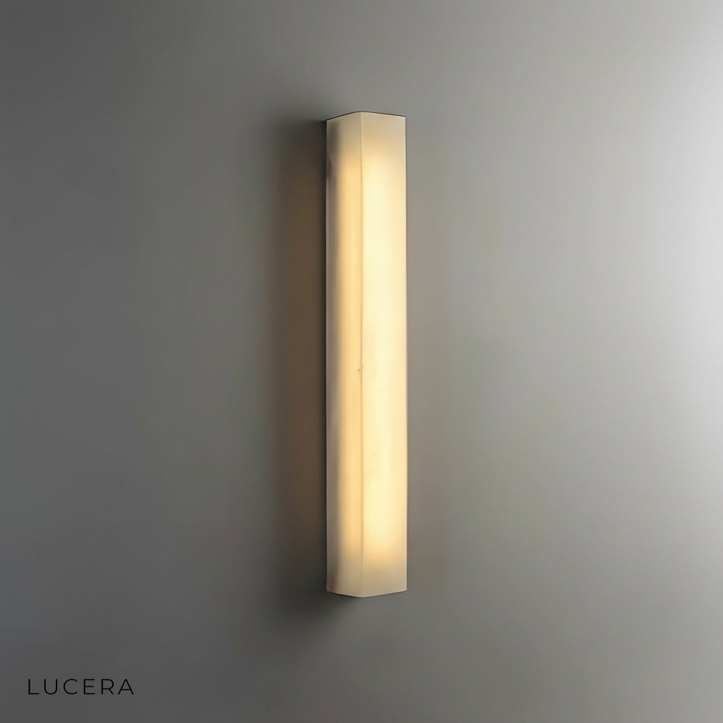 Varenna marble sconce mounted above bed in cozy bedroom with soft ambient light