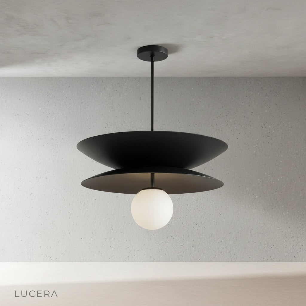 Tremulous pendant light in polished brass finish suspended in minimalist studio setting