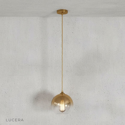 Green gold pendant light hanging above a wooden dining table in contemporary dining room