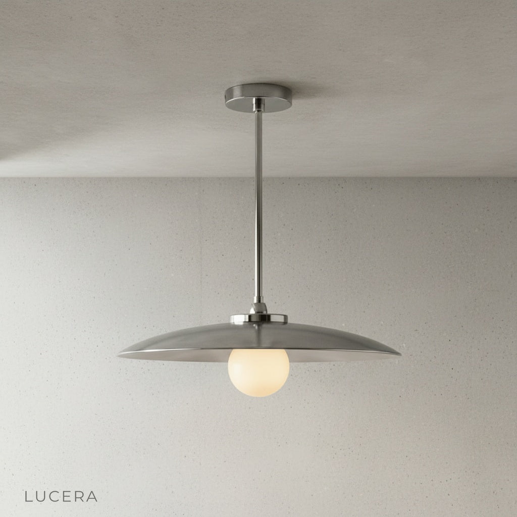 Sculptural brass pendant light above a wooden counter in a bright interior