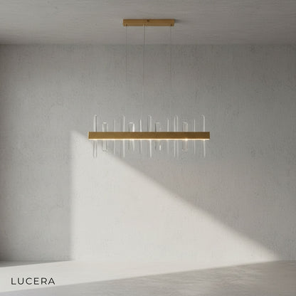 Rectangular gold crystal chandelier hanging above marble dining table in bright space