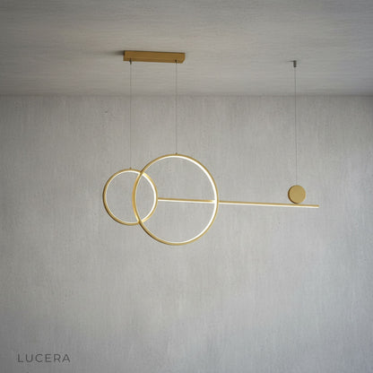 Brumal pendant light gold variant hanging above dining table with soft glow