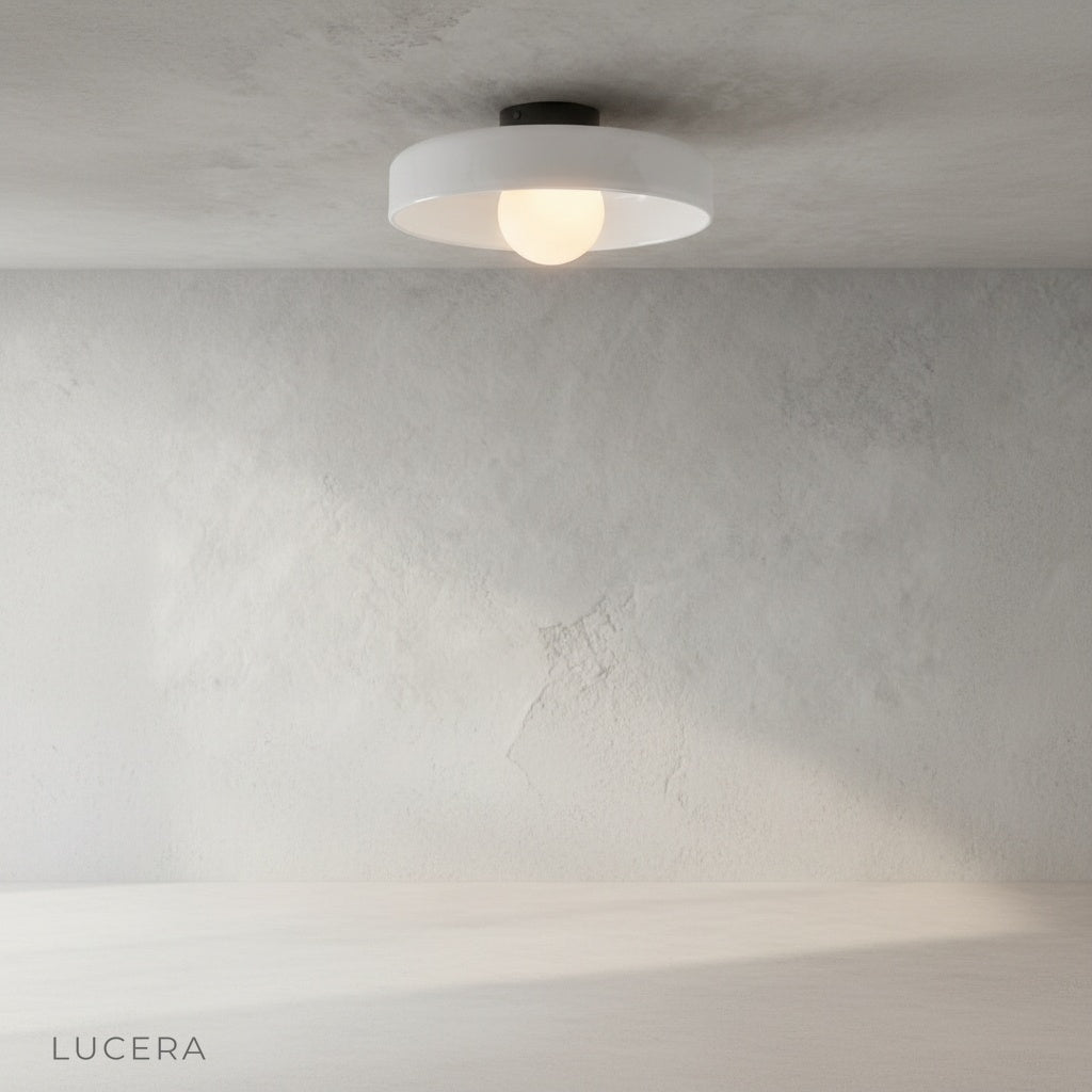 Madder ceiling light as wall sconce in a cozy reading nook, colored glass body glowing against neutral wall