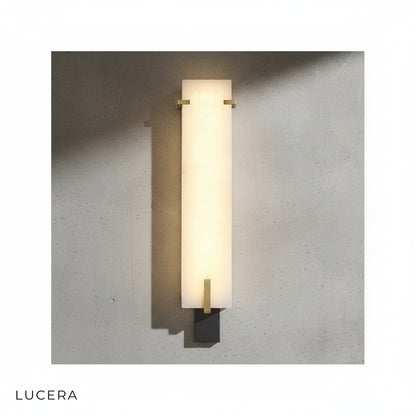 Antique style marble wall sconce glowing in minimalist entryway with stone wall