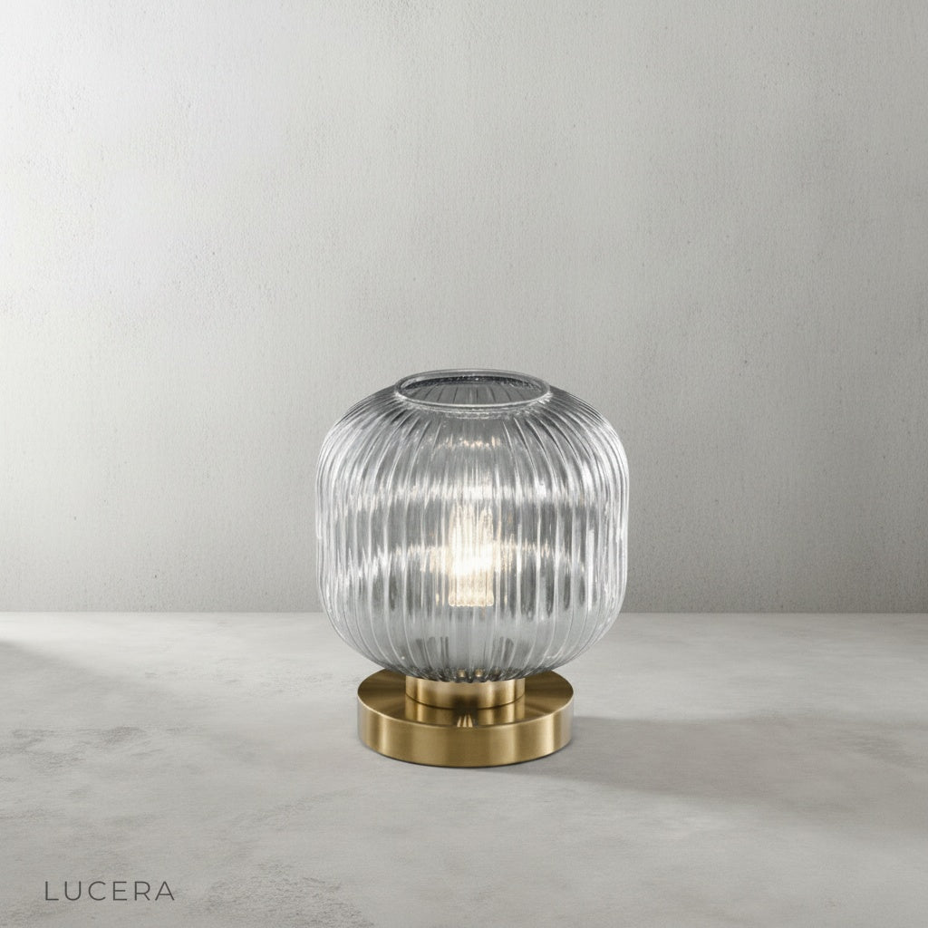 ribbed glass table lamp with brass accents on dark oak shelf in study