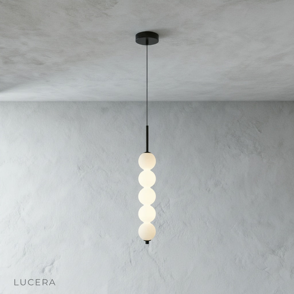eight-head Meridian Pendant Light suspended over modern study desk with warm daylight