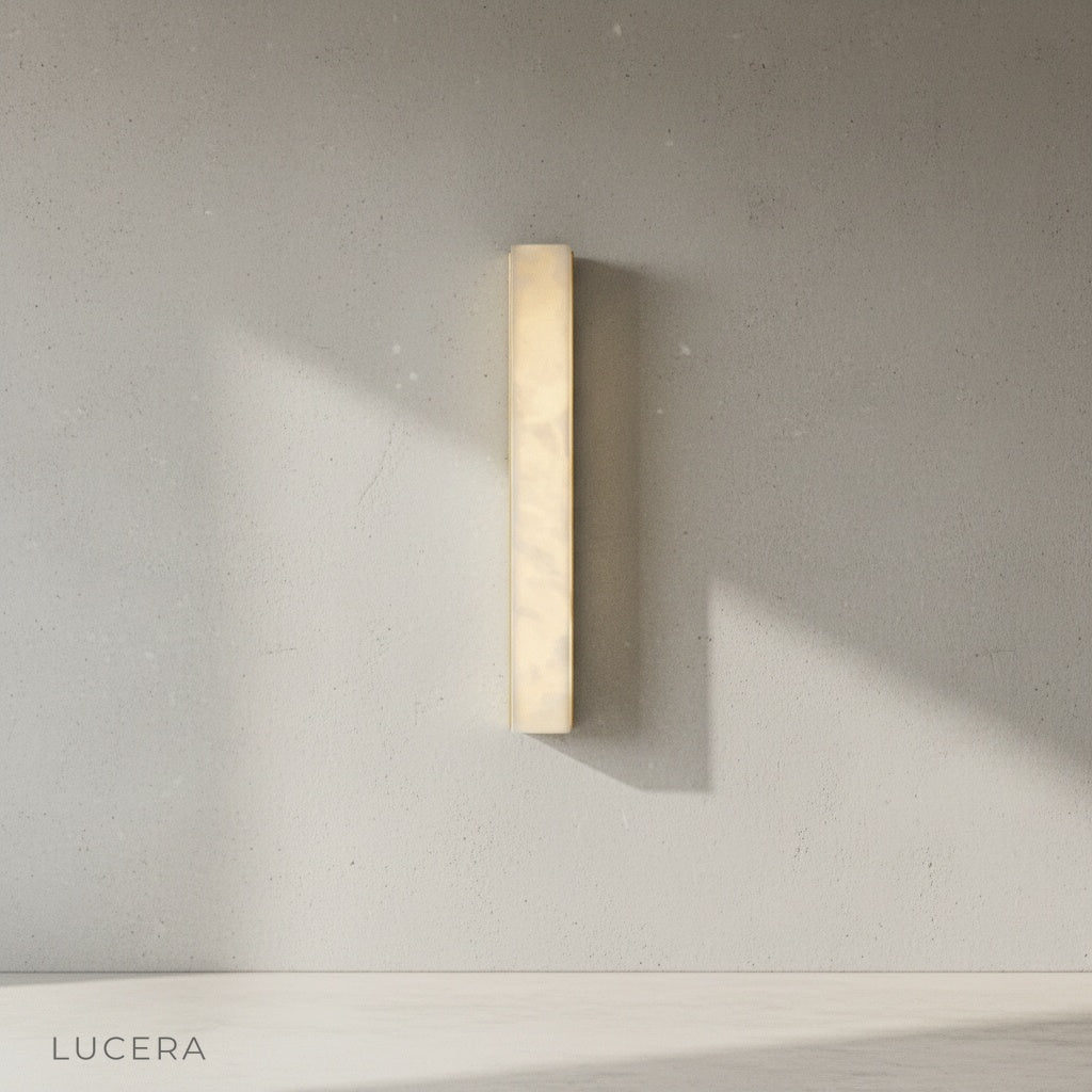 Brass and alabaster wall light illuminating dark brown wall in contemporary entryway