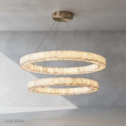 Evening shot of the round alabaster chandelier casting a golden glow over a rustic wooden table