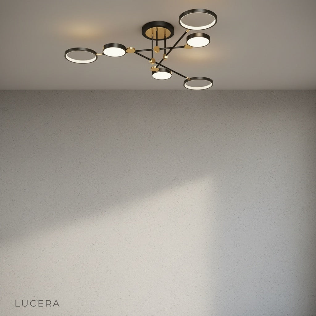 Yin-yang ceiling light with gold linear arms casting patterned shadows on neutral wall