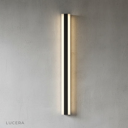 Drambuie lamp in nighttime ambiance illuminating dark charcoal exterior wall