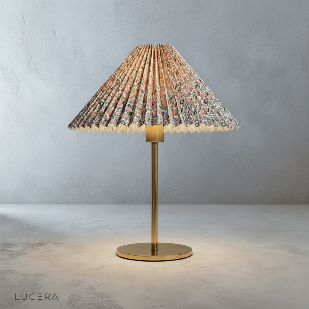 Ysabel Table Lamp illuminating a reading nook with an armchair and soft throw blanket