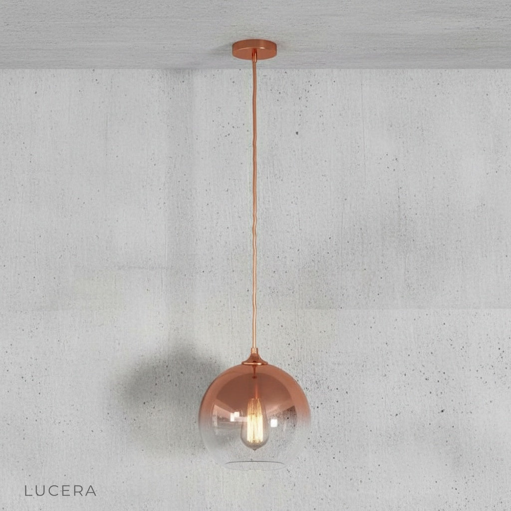 Green gold glass pendant light glowing at dusk in a stylish modern living room